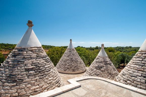 Trulli houses with conical roofs set against a clear blue sky.