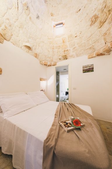 Cozy bedroom with a stone ceiling, double bed, and a tray with refreshments.